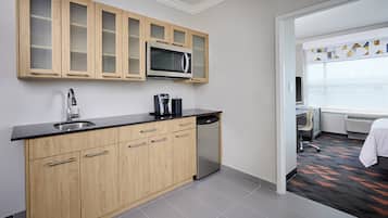 A modern kitchen with wooden cabinets, a stainless steel sink, and a microwave.