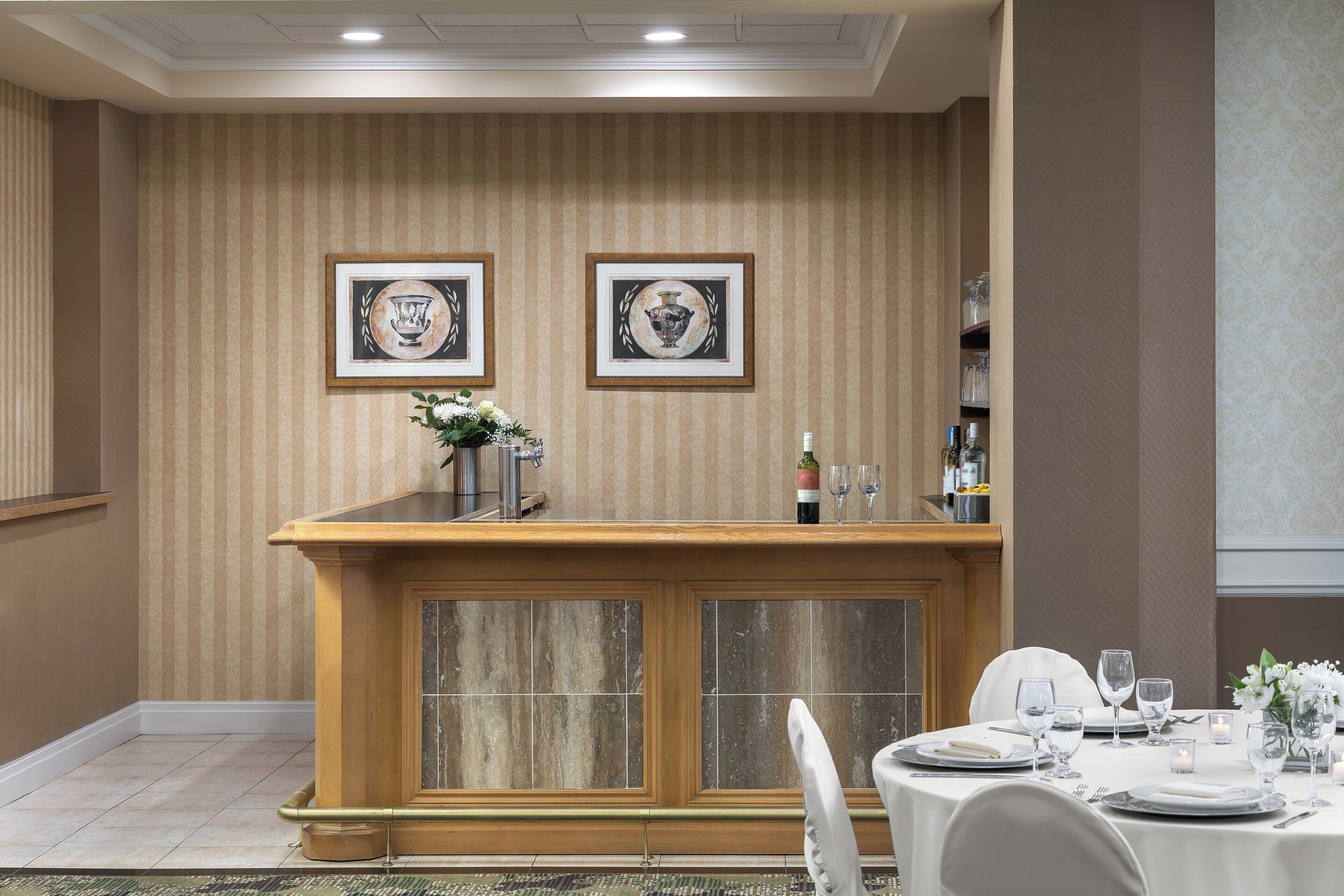 A formal dining area with a wooden counter, framed artwork, and a table set for a meal.
