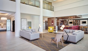A spacious lobby with a high ceiling, a bar area, and a seating area with sofas and chairs. - Holiday Inn Hotel & Suites Oakville @ Bronte by IHG (Oakville)