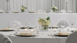 Una mesa dispuesta para un evento formal, con manteles blancos, copas y velas.
