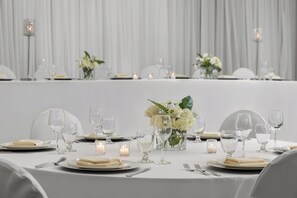 A table set for a formal event with white tablecloths, glassware, and candles. - Holiday Inn Hotel & Suites Oakville @ Bronte by IHG (Oakville)