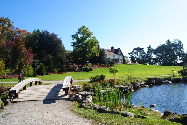 A wooden bridge over a pond, a house with a lawn, and a clear blue sky. - Holiday Inn Hotel & Suites Oakville @ Bronte by IHG (Oakville)