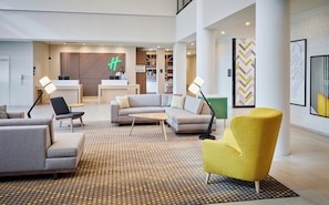 A modern hotel lobby with a reception desk, seating area, and a patterned carpet. - Holiday Inn Hotel & Suites Oakville @ Bronte by IHG (Oakville)