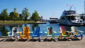 A waterfront view with colorful Adirondack chairs and a large yacht docked near the water. - Holiday Inn Hotel & Suites Oakville @ Bronte by IHG (Oakville)