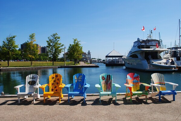 A waterfront view with colorful Adirondack chairs and a large yacht docked near the water. - Holiday Inn Hotel & Suites Oakville @ Bronte by IHG (Oakville)