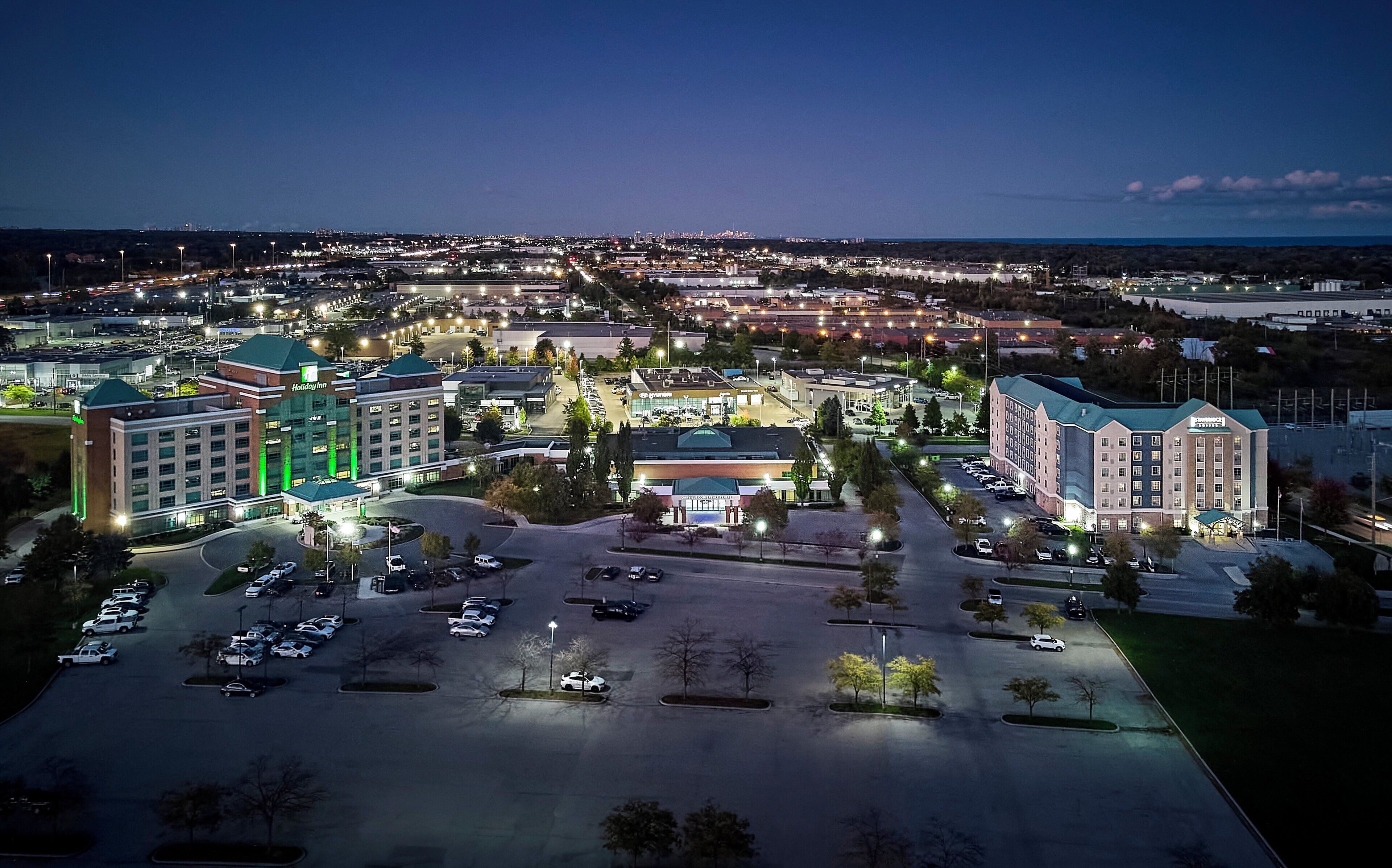 A large hotel complex with multiple buildings, a parking lot, and surrounding urban area.