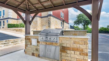 An outdoor grill area with stone walls and a metal roof structure.