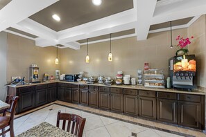 A modern kitchen with a coffee station, microwave, and various food items.