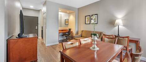 A dining area with a wooden table and chairs, a small cabinet, and a lamp.