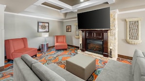 A living room with a fireplace, two red chairs, a grey sofa, and a flat-screen TV. - Best Western Plus Georgetown Inn & Suites (Georgetown)