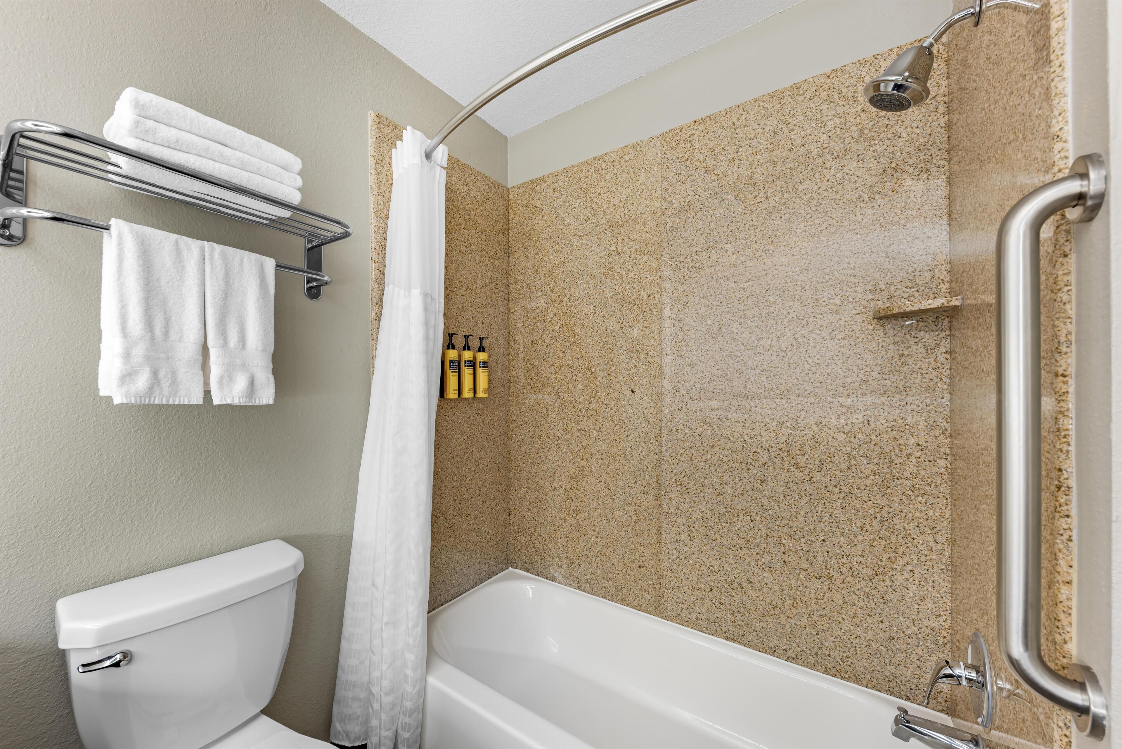 A bathroom with a toilet, a bathtub, a shower, and a towel rack.