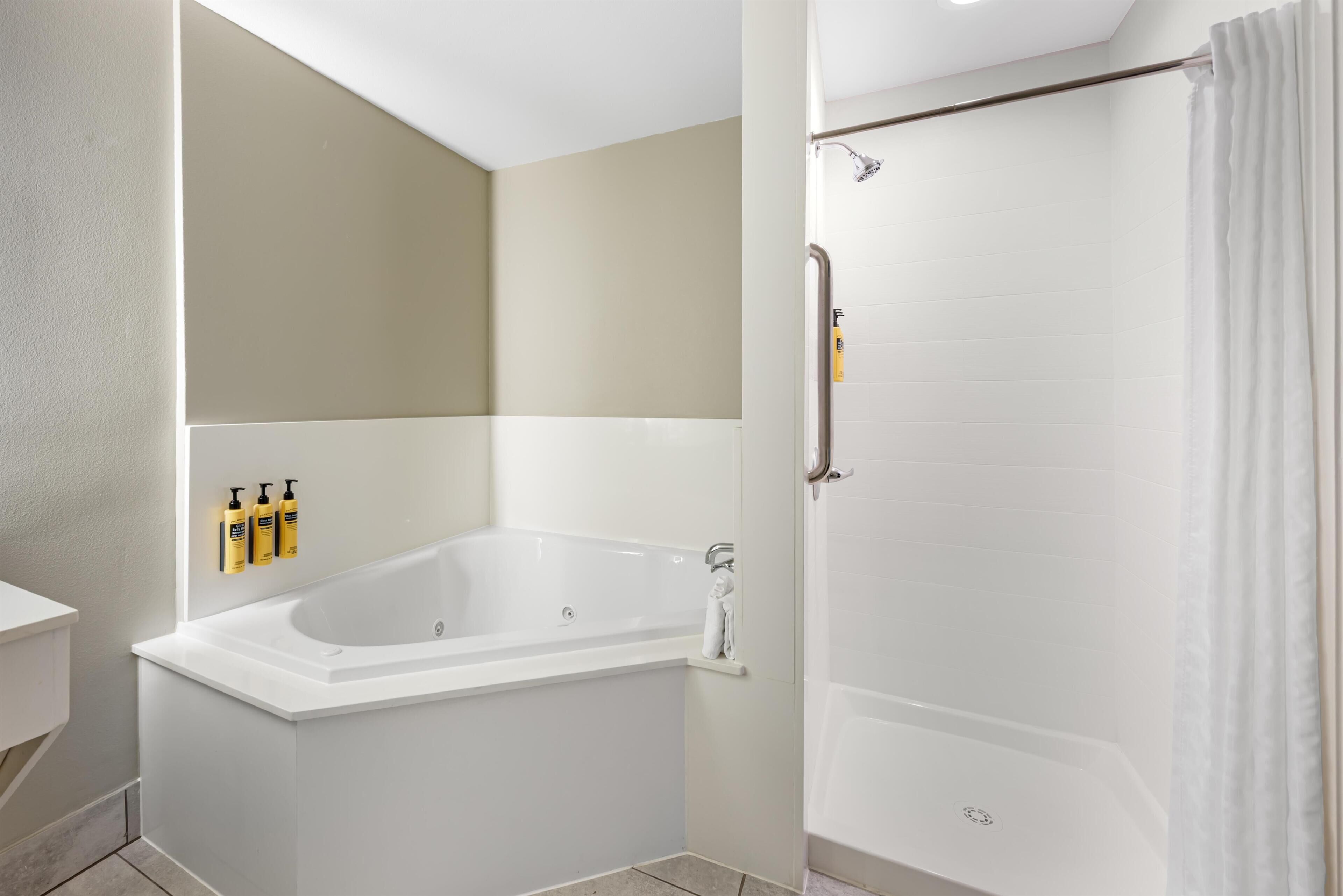 Een moderne badkamer met een bad, douche en een handdoekrek met toiletartikelen.