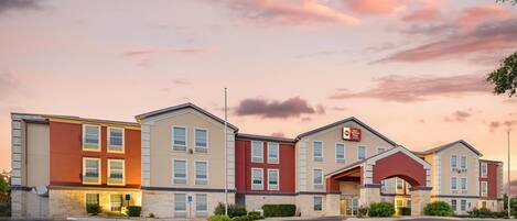 A multi-story hotel with a red and beige facade, multiple windows, and a parking lot.