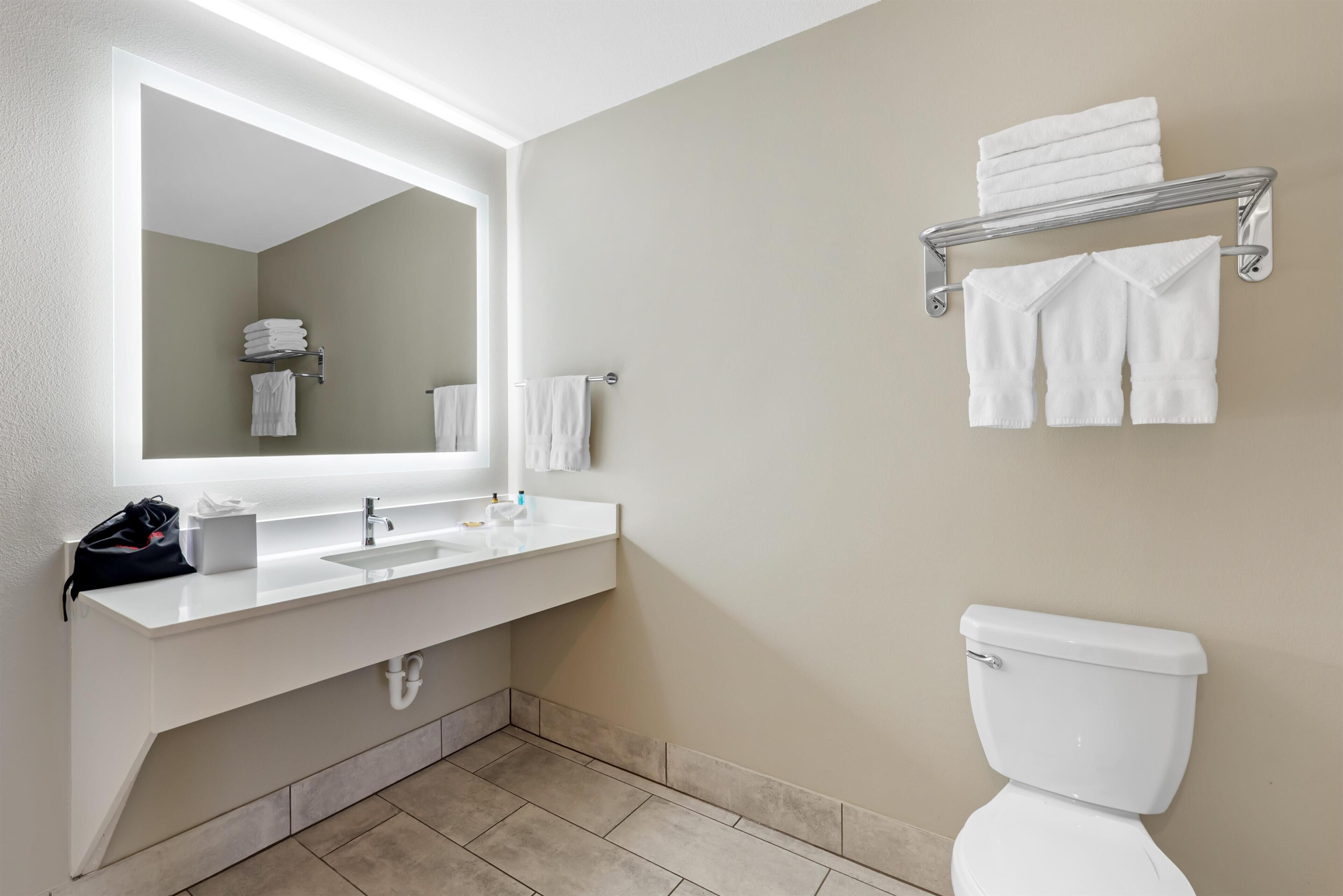 A bathroom with a white sink, mirror, and toilet.