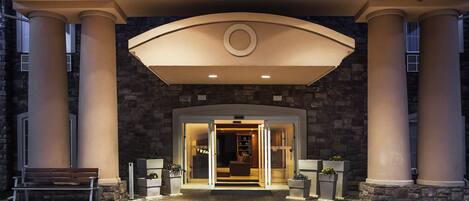 A building entrance with a stone facade, large columns, and a covered entryway.