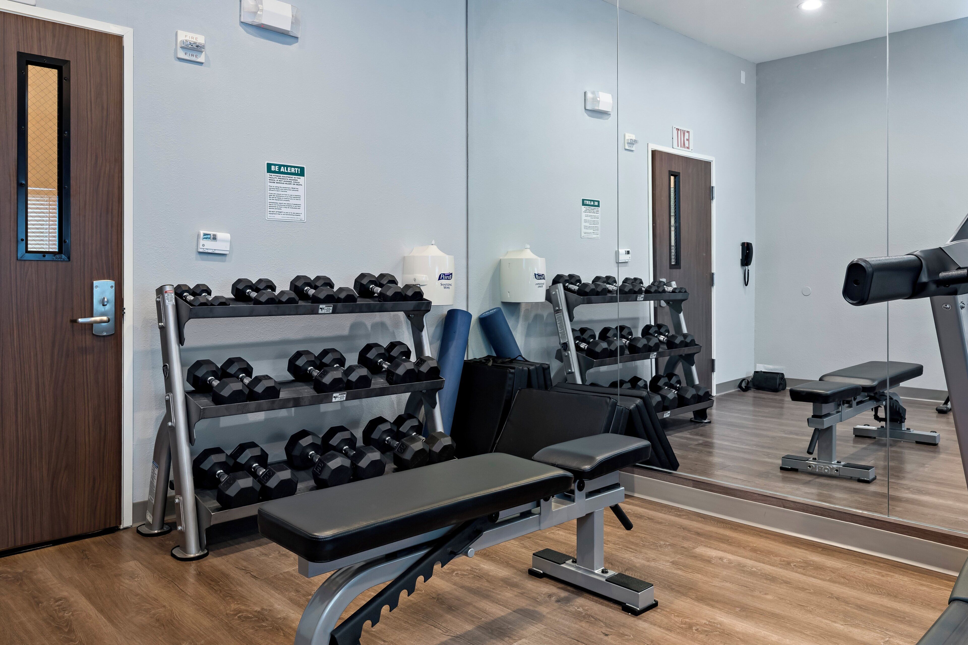 A gym with exercise equipment, including dumbbells, benches, and a treadmill.