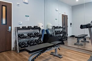Un gimnasio con equipo de ejercicio, incluyendo mancuernas, bancos y una cinta de correr.