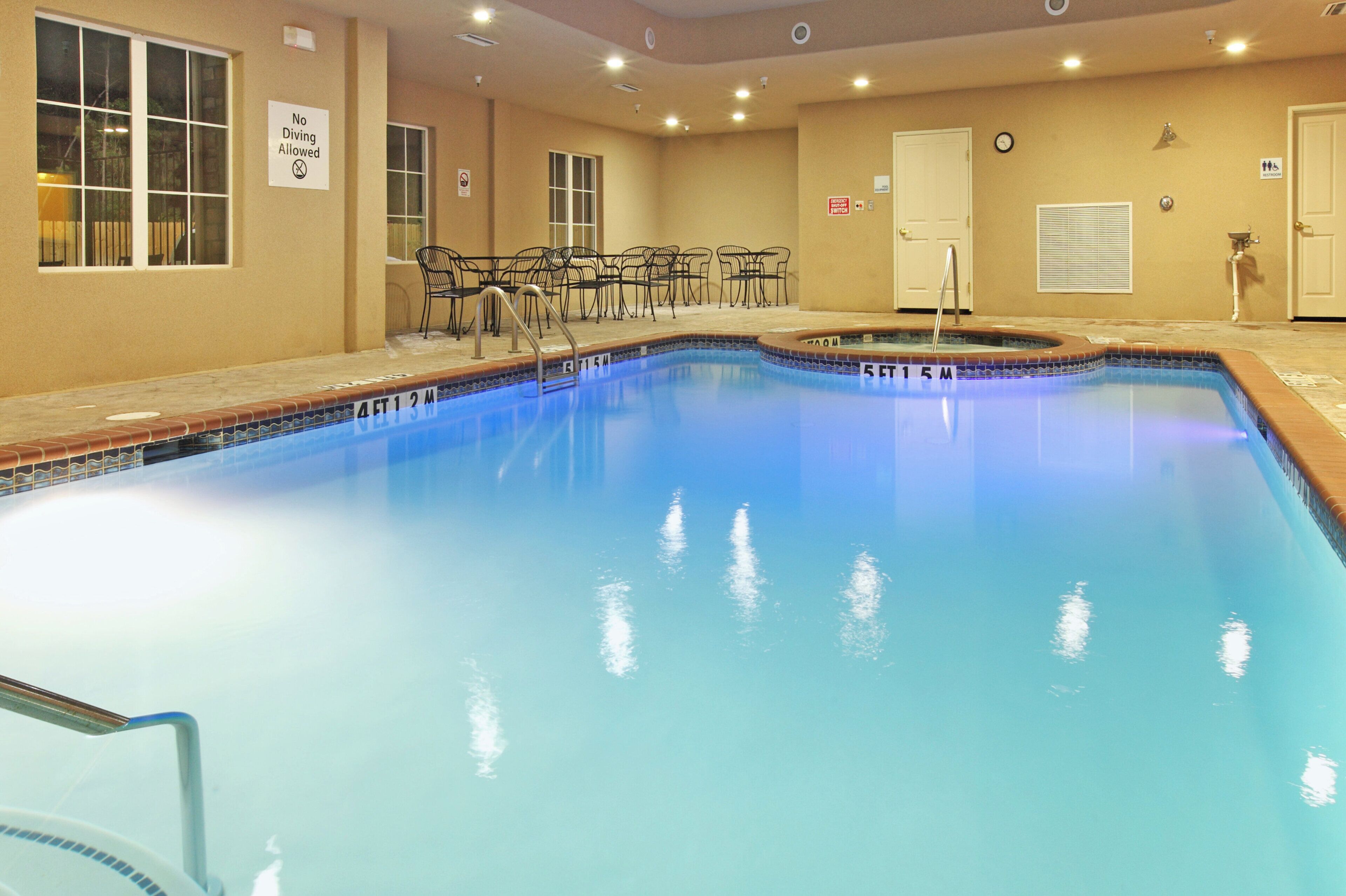 A swimming pool with a diving sign, a clock, and a sign indicating a restroom.