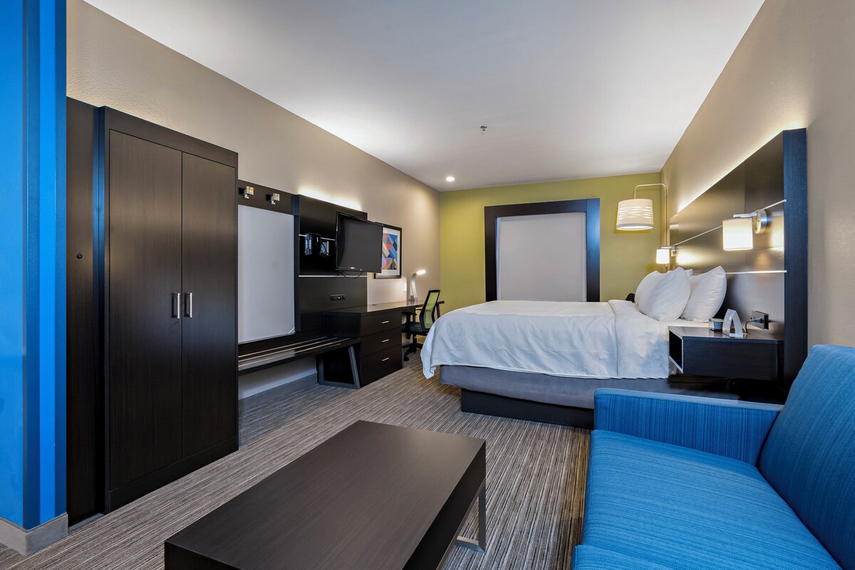 A hotel room with a bed, a desk, a wardrobe, a TV, and a sofa.