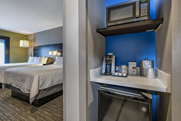 A hotel room with a bed, bedside table with a coffee maker, microwave, and a mini fridge. - Holiday Inn Express Hotel & Suites Kilgore by IHG (Kilgore)