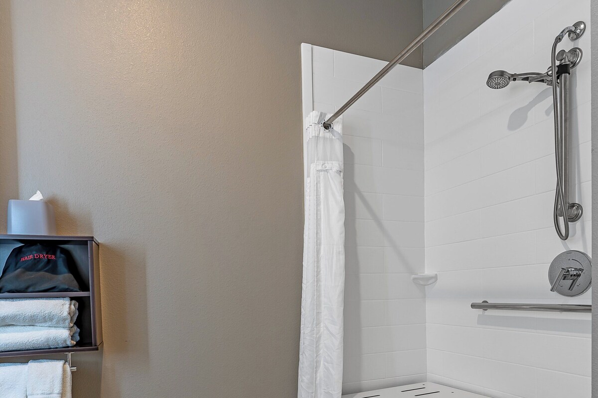A shower area with a showerhead, a towel rack, and a bench.