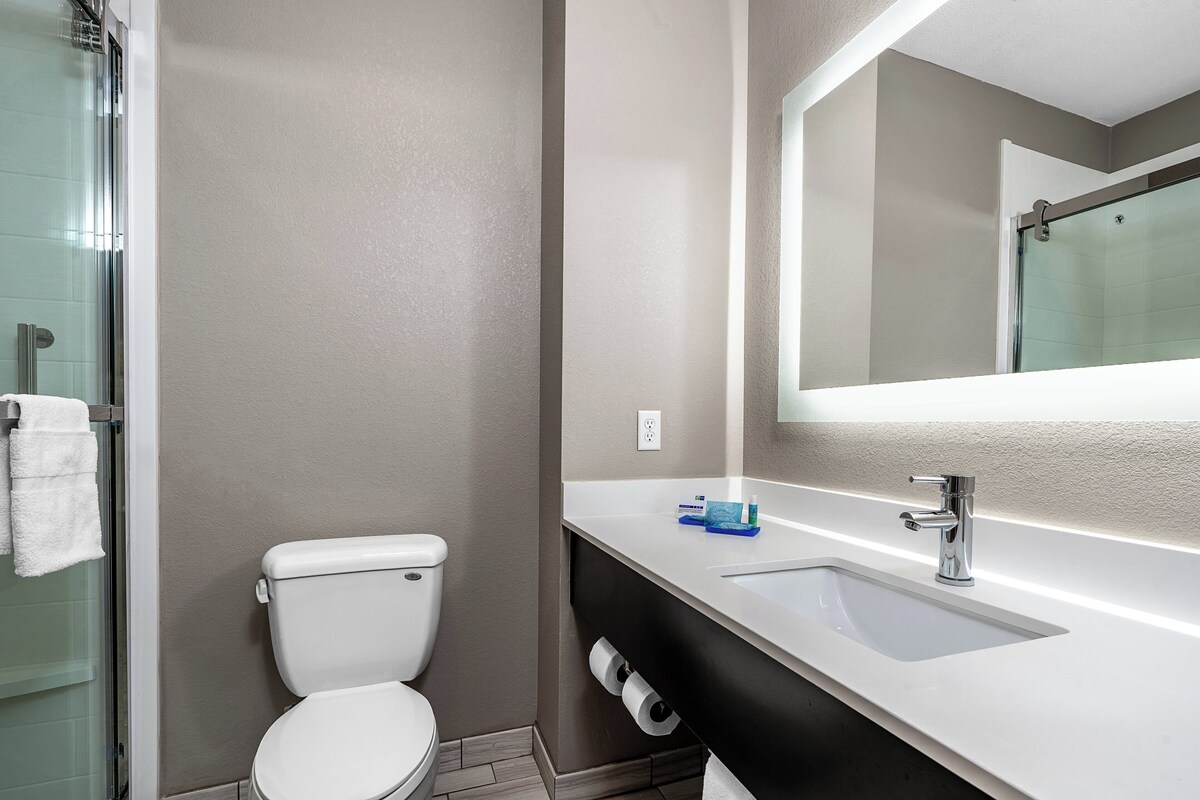 A modern bathroom with a toilet, sink, and glass shower enclosure.