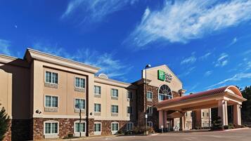 Un hôtel Holiday Inn Express & Suites, avec un bâtiment à deux étages, une entrée couverte et un ciel d’un bleu éclatant.