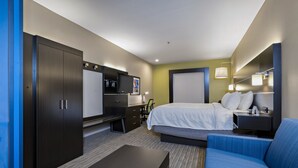 Quarto de hotel com cama, escrivaninha, guarda-roupa e sofá.