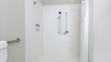 A white shower room with a glass door, a handheld showerhead, a wall-mounted faucet, and a towel rack.