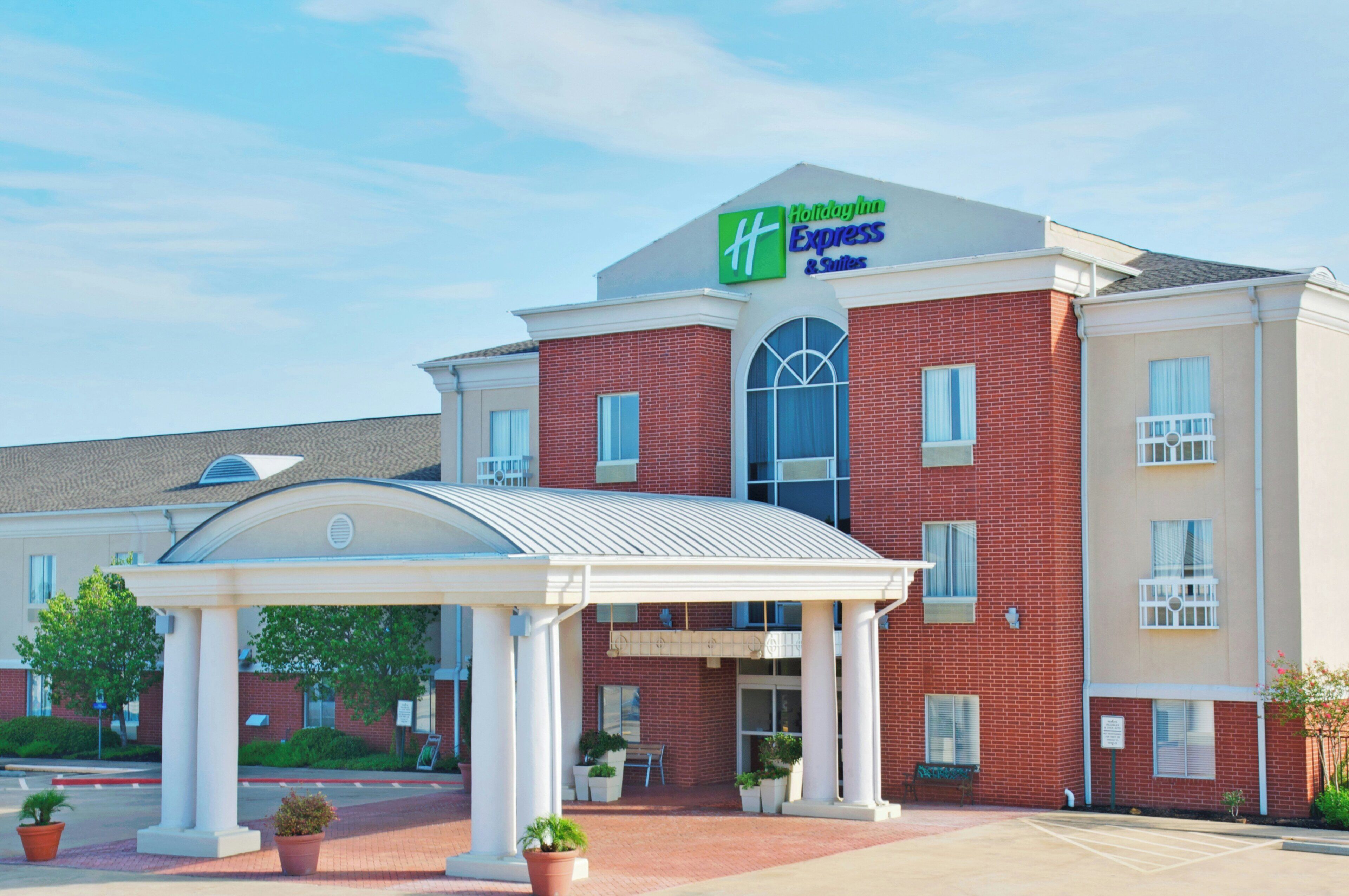 Un hotel Holiday Inn Express & Suites con fachada de ladrillo, entrada cubierta y estacionamiento.