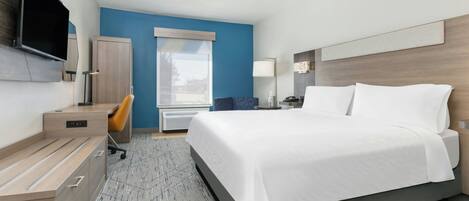 A hotel room with a bed, desk, chair, TV, wardrobe, and a window.