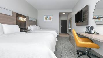 A hotel room with two beds, a desk, a chair, a TV, and a bathroom door.