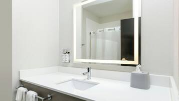Ein Badezimmer mit einem weißen Waschbecken, einem Spiegel mit Beleuchtung und einem Handtuchhalter.