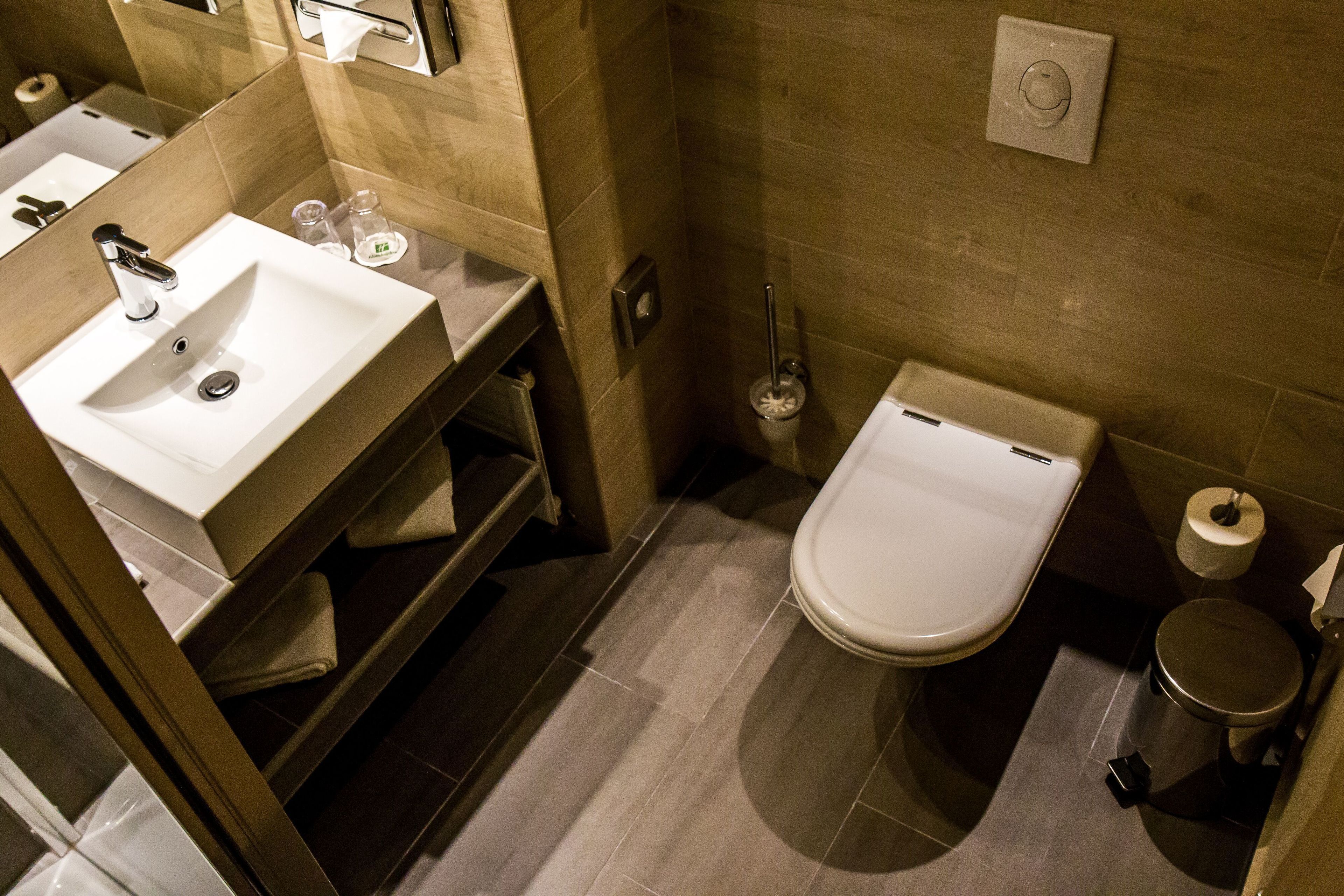 A modern bathroom with a sink, toilet, and a trash bin.