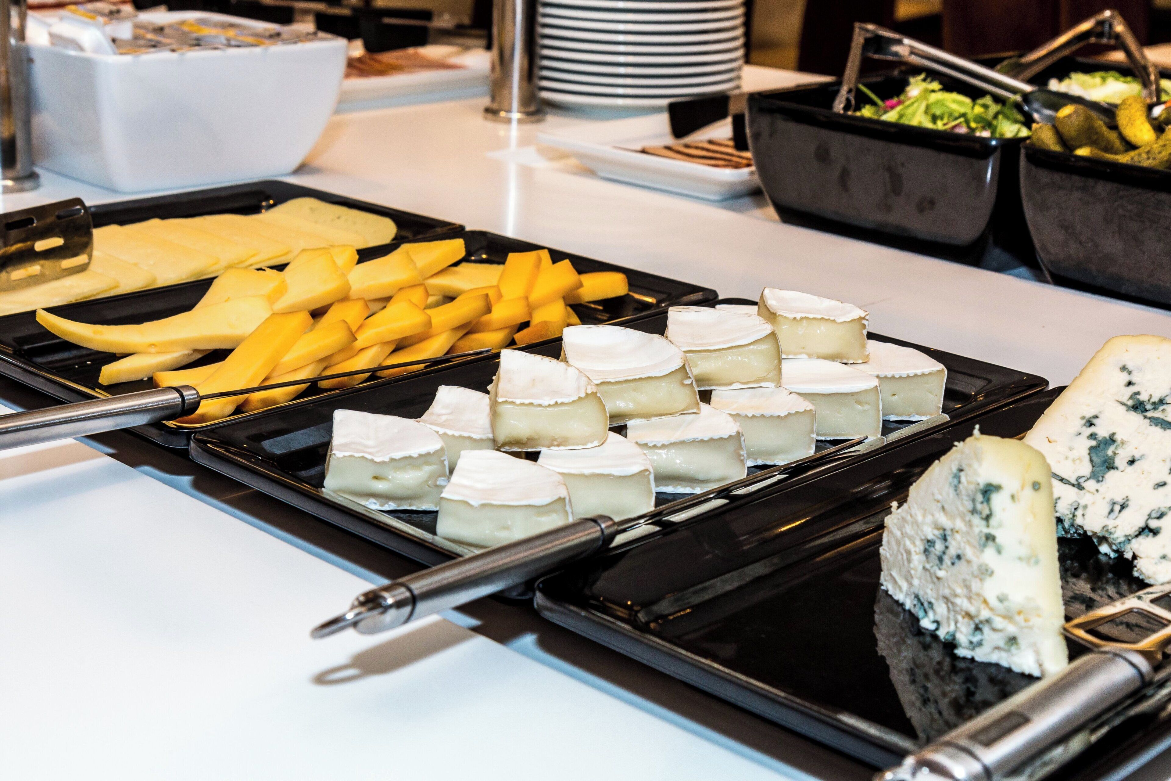 A buffet with various cheeses, fruits, and vegetables.