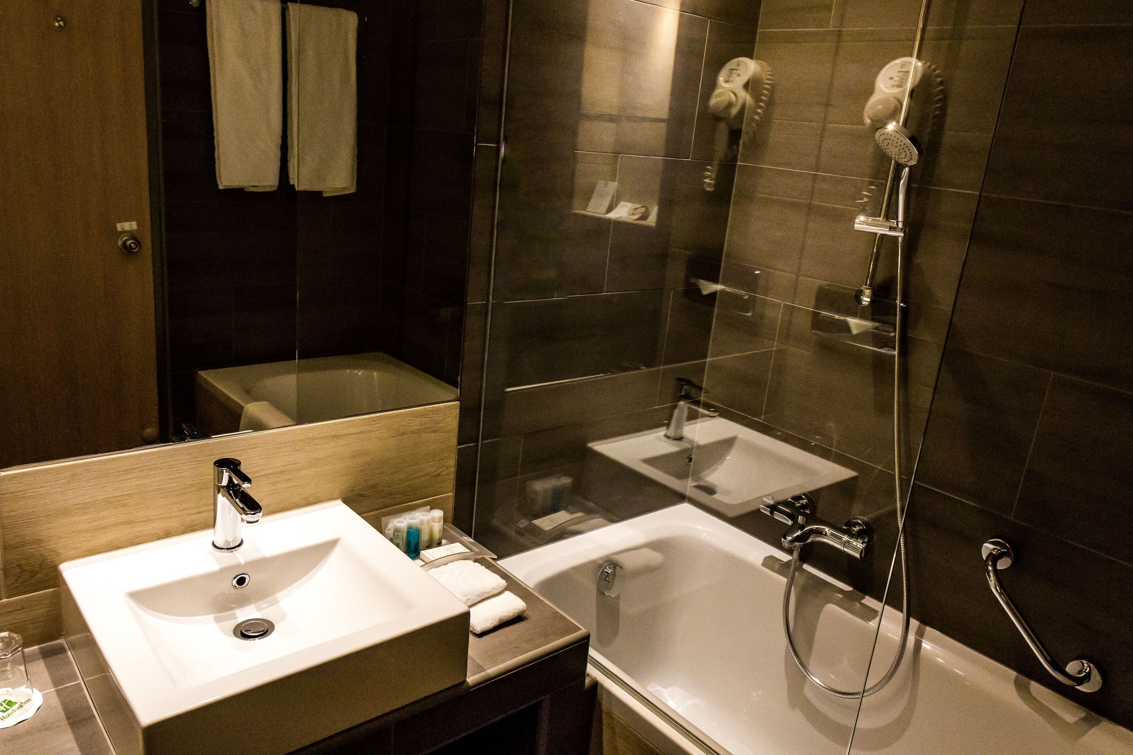 A modern bathroom with a sink, mirror, and bathtub.