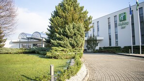 Ein Holiday Inn Hotel mit einem modernen Gebäude, einem gepflegten Rasen und blauem Himmel.