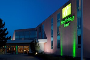 A Holiday Inn hotel with a modern facade, large windows, and a well-lit entrance.