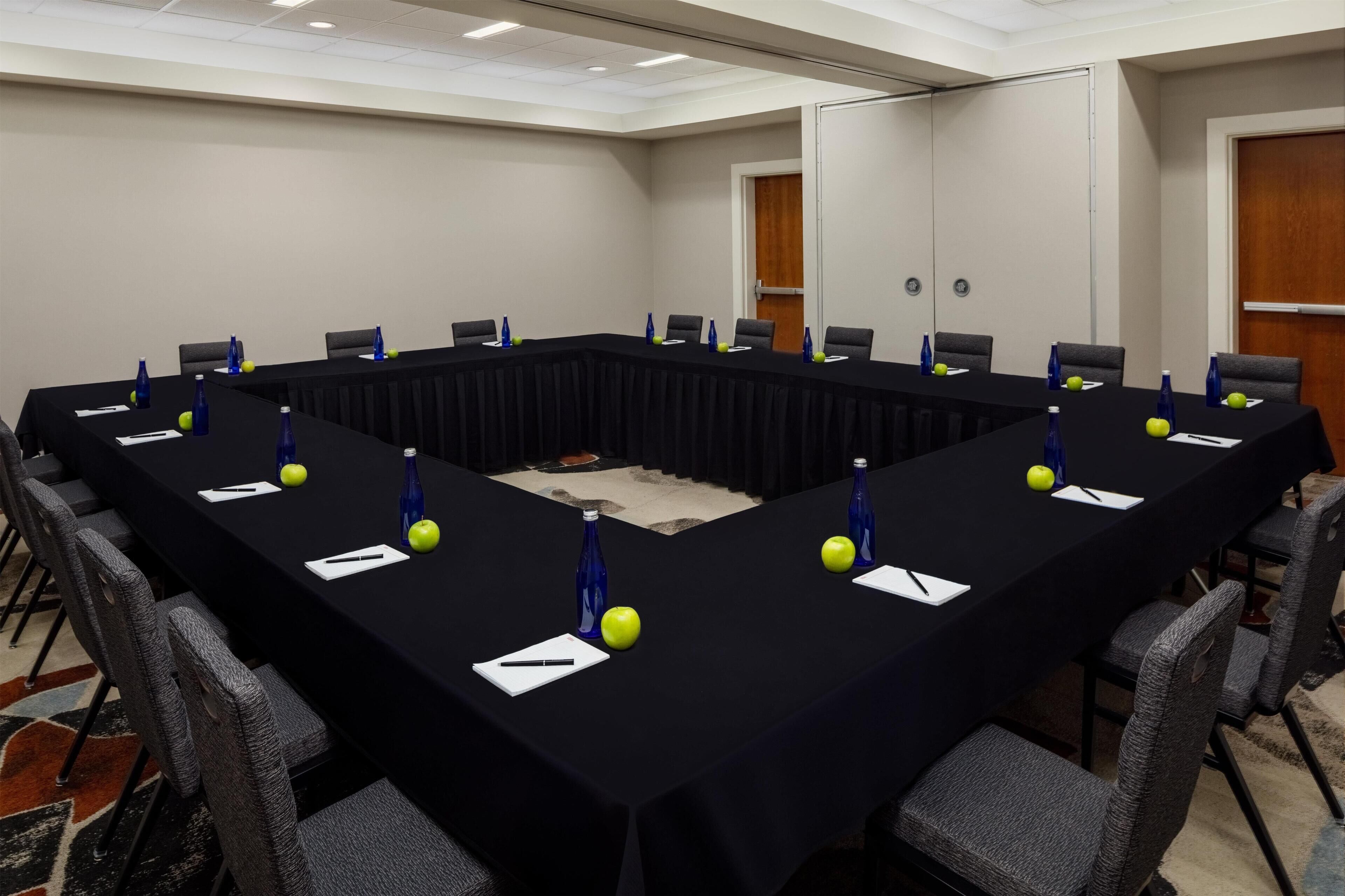 Una sala de conferencias con una larga mesa, sillas y botellas de agua.