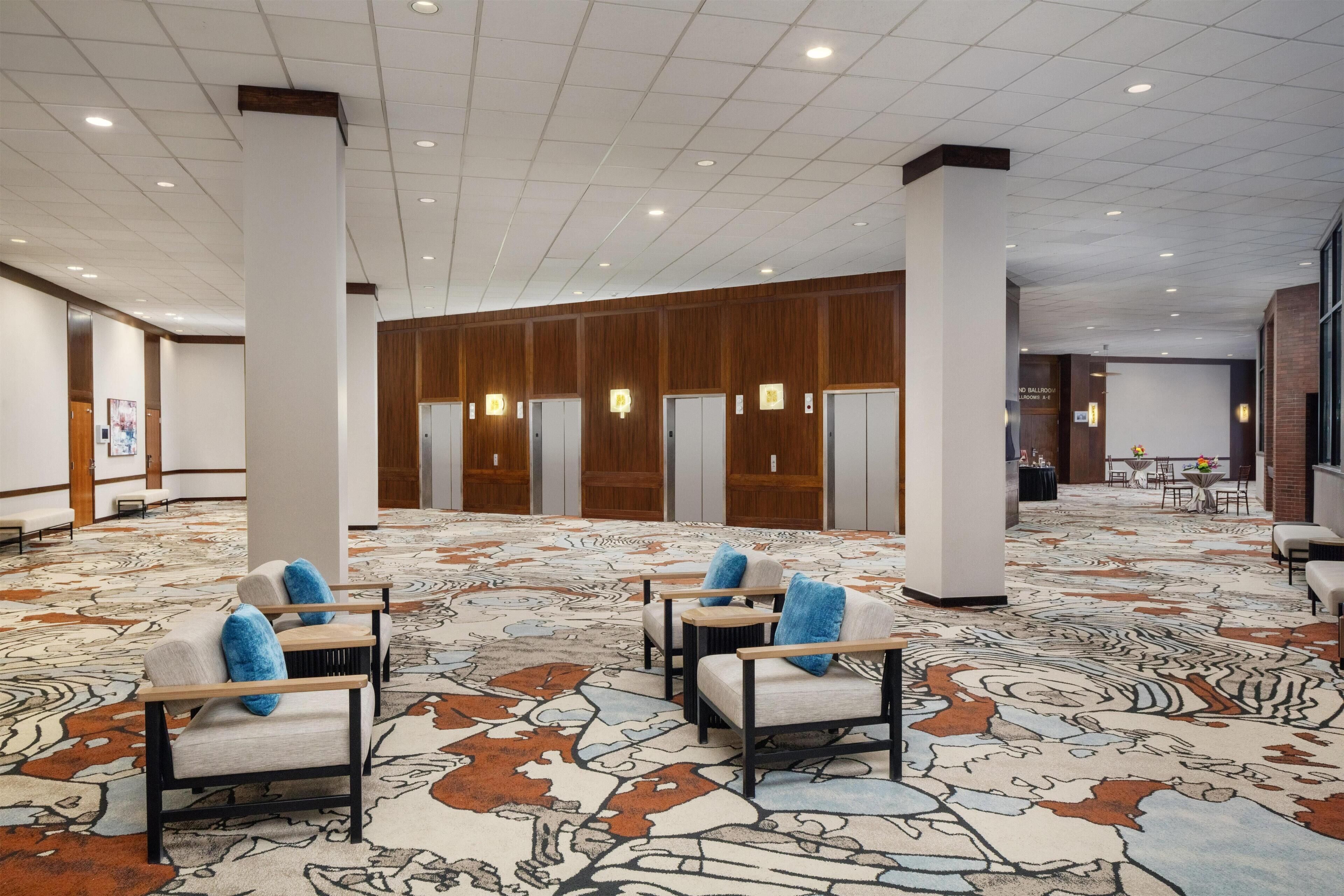 Eine geräumige Lobby mit einem gemusterten Teppich, einer Sitzecke und Wandverkleidungen aus Holz.