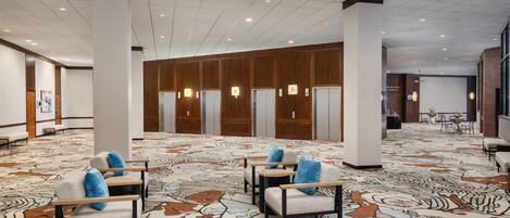 Eine geräumige Lobby mit einem gemusterten Teppich, einer Sitzecke und Wandverkleidungen aus Holz.