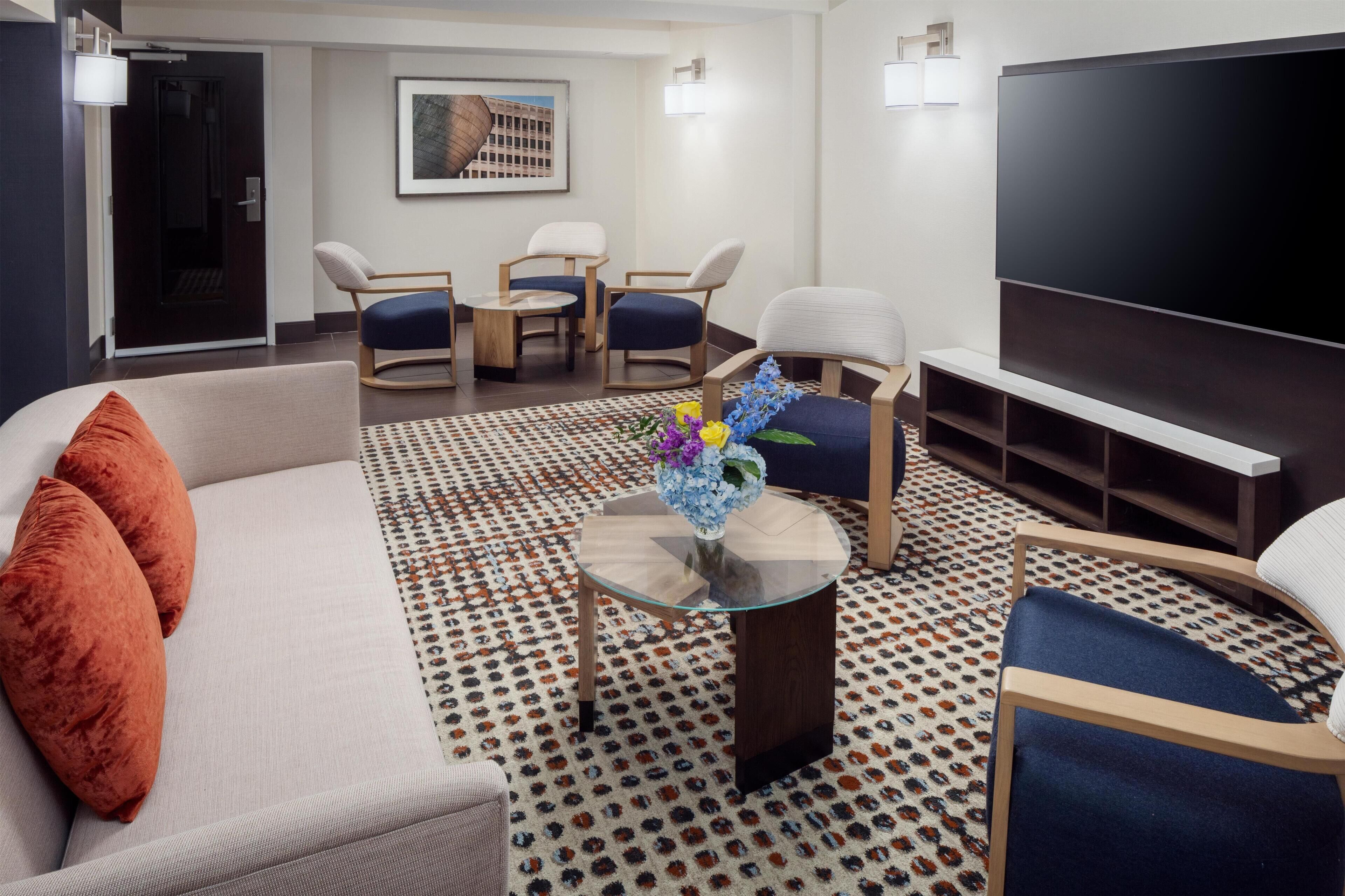 A modern living room with a sofa, chairs, a coffee table, and a flat-screen TV.