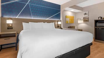 A hotel room with a large bed, bedside tables, a desk, and a modern wall design.