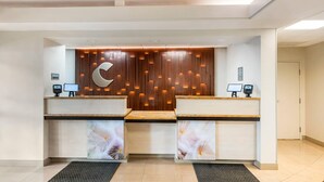 A reception desk with a wooden panel wall, two computer stations, and a large logo. - Comfort Inn & Suites Saint Louis Lafayette Square (St. Louis)