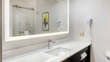 Un bagno moderno con uno specchio grande, un lavandino, un asciugacapelli e un telefono.