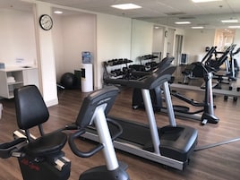 Un gimnasio con cintas de correr, una bicicleta estática y pesas sueltas.