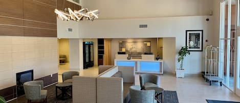 A hotel lobby with a reception desk, seating area, and a large window.
