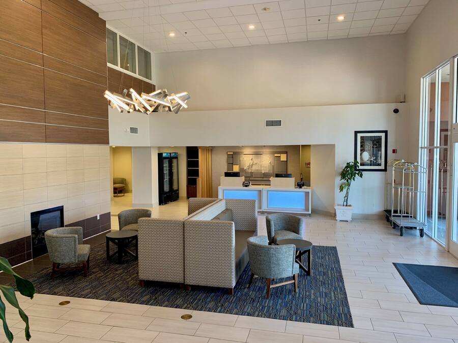 A hotel lobby with a reception desk, seating area, and a large window.