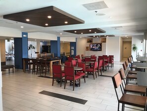 A spacious indoor area with multiple seating arrangements, including tables and chairs, and a television mounted on the wall. - Holiday Inn Express Hotel & Suites Tracy by IHG (Tracy)