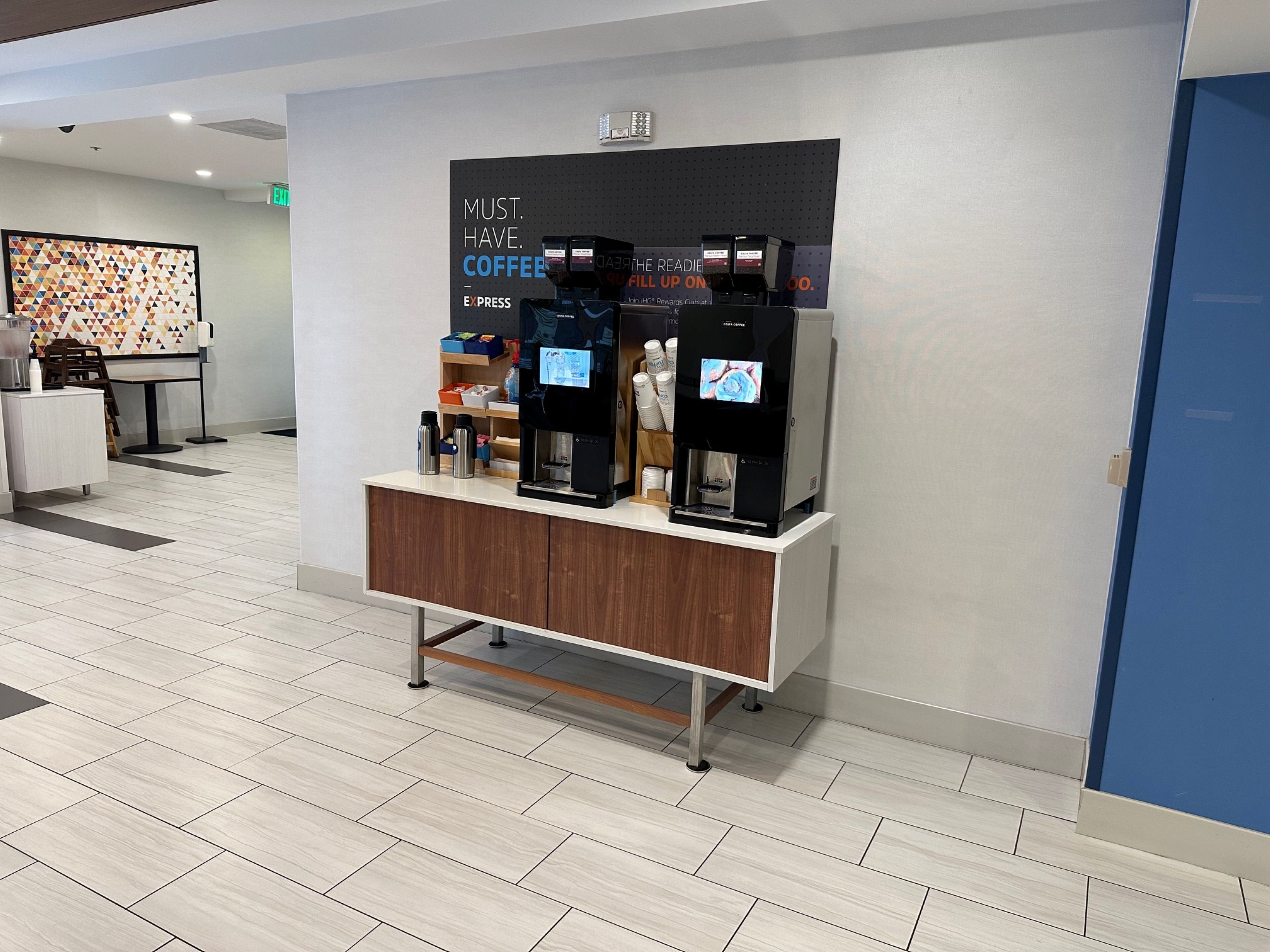 A coffee station with multiple coffee dispensers and a counter.